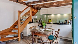 Una cucina con una scala in legno, un tavolo da pranzo con sedie e una porta verde.