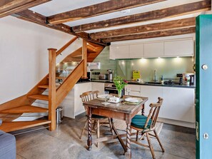 A kitchen with a wooden staircase, a dining table with chairs, and a green door. - 1 Bed in Bristol (oc-95178) (Blagdon)