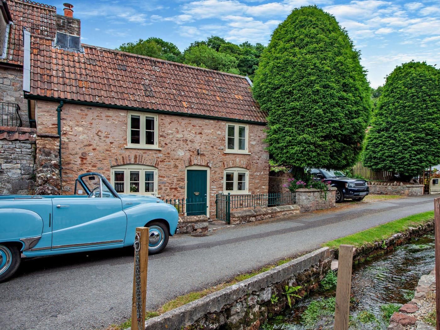 A stone building with a tiled roof, a narrow road, and a small water channel.