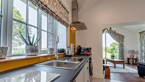 A modern kitchen with a large window, a dining area with a table and chairs, and a view of the outdoors. - 2 Bed in Llanarth (oc-95322) (Llanarth)
