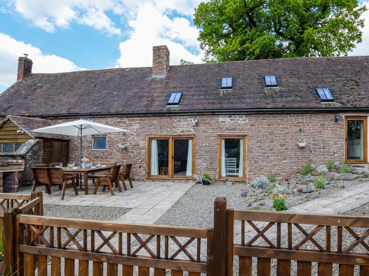 A stone building with a patio area, outdoor seating, and a wooden fence.
