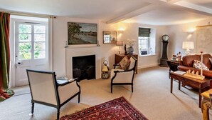 A living room with a fireplace, two armchairs, a sofa, a rug, and a large window with curtains. - 3 Bed in Kelso (oc-95231) (Kelso)