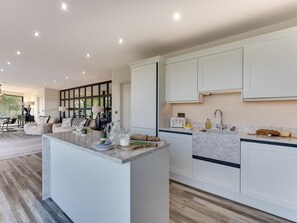 A modern kitchen with white cabinetry, a marble countertop, and a built-in island.