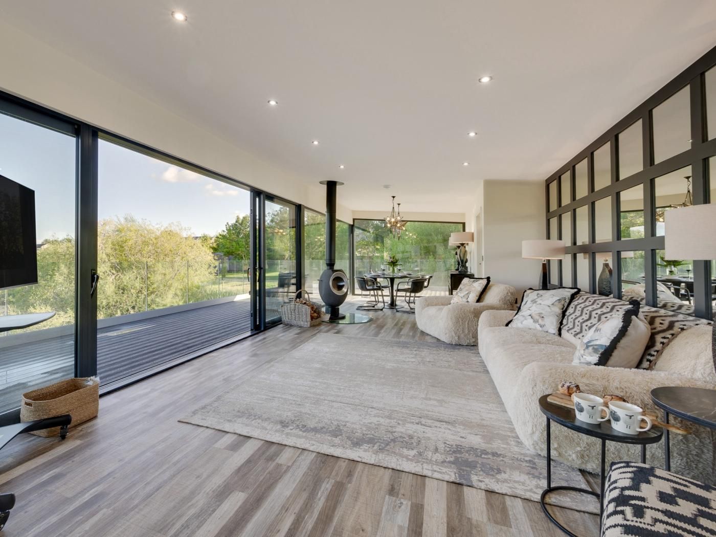 Een moderne woonkamer met een grote bank, een eethoek en een open haard.