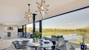 Uma sala de jantar moderna com uma mesa grande, cadeiras e luminárias pendentes em formato de estrela.