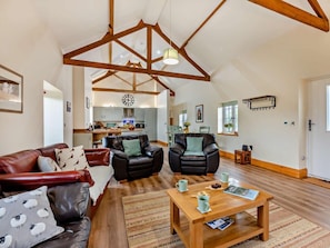 A spacious living area with a high ceiling, wooden beams, a dining area, and a kitchen. - 4 Bed in Spennymoor (oc-95189) (Byers Green)