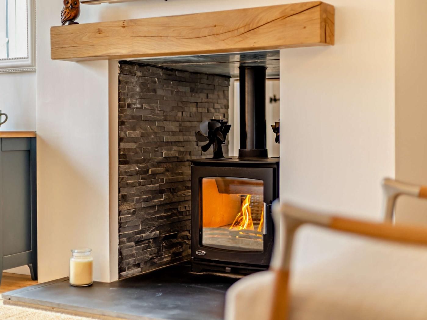Ein modernes Wohnzimmer mit Kamin aus Stein, einem hölzernen Sims und einer Glastür.
