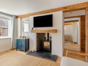 Ein Zimmer mit Kamin, einem darüber angebrachten Fernseher und einem blauen Schrank links.