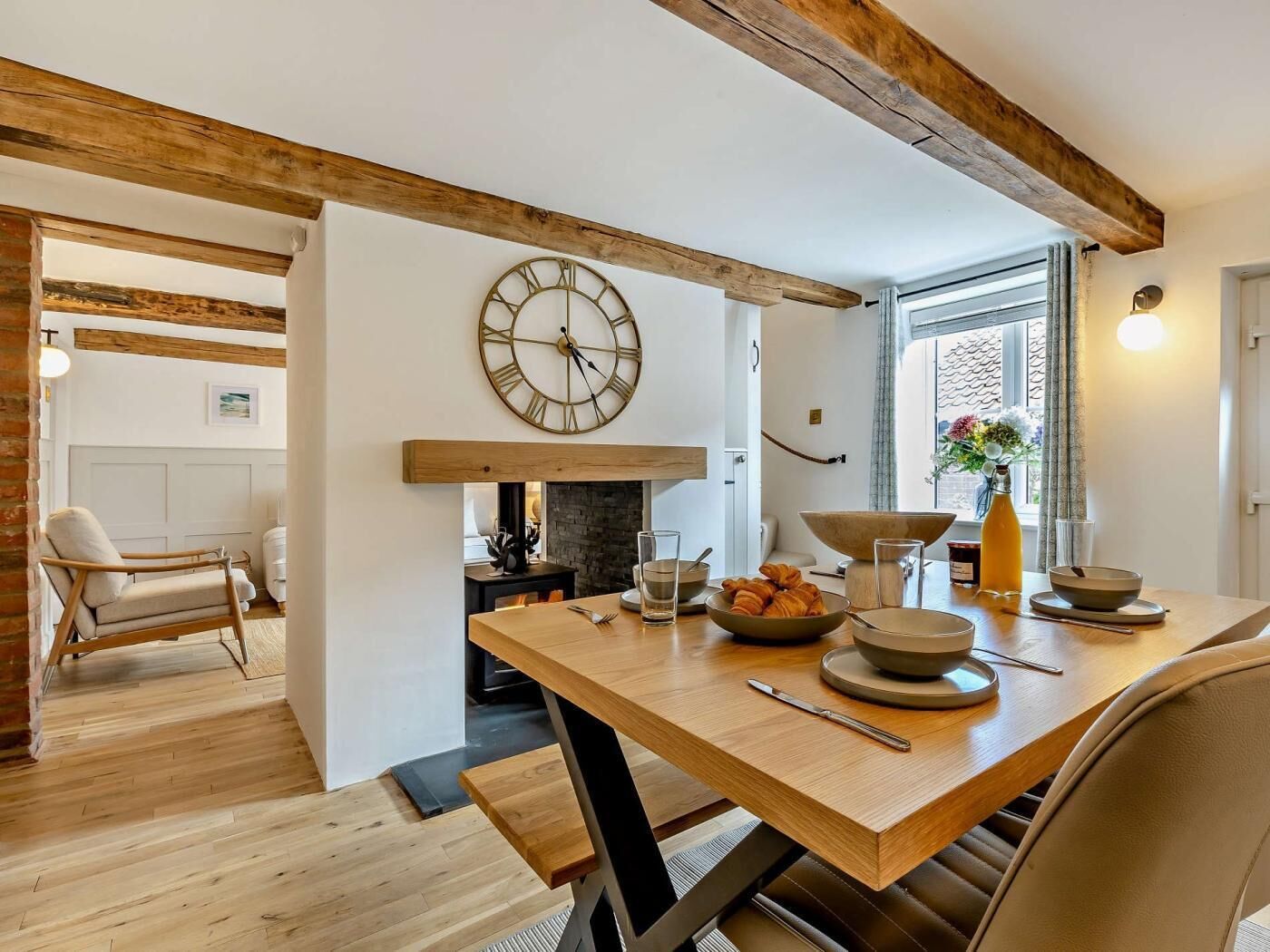 A dining area with a wooden table, chairs, a clock, and a fireplace.