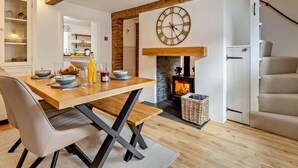 Comedor con una mesa de madera, sillas, un reloj y una chimenea.