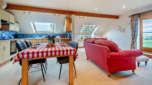 Eine moderne Küche mit Esstisch, rot-weiß kariertem Tischläufer und einem roten Sofa.