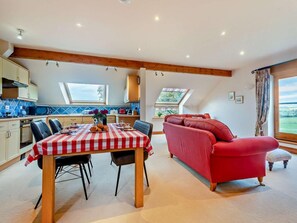 Eine moderne Küche mit Esstisch, rot-weiß kariertem Tischläufer und einem roten Sofa.