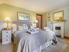 A neatly arranged bedroom with a bed, bedside lamps, a fireplace, and a framed picture on the wall. - 1 Bed in Keswick (oc-87483) (Applethwaite)