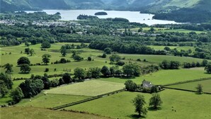 A rural landscape with rolling hills, a lake, and scattered buildings. - 1 Bed in Keswick (oc-87483) (Applethwaite)