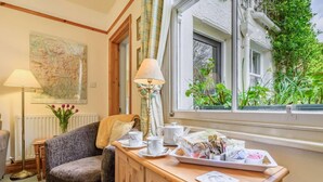 A cozy room with a wooden cabinet, a chair, a map on the wall, and a window with greenery outside. - 1 Bed in Keswick (oc-87483) (Applethwaite)