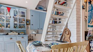 A dining area with a table set for two, a bookshelf, and a cabinet with decorative items. - 1 Bed in Lymington (oc-94751) (Lymington)