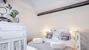 A bedroom with a bed, bedside table, lamp, dresser, and a decorative vase with flowers. - 1 Bed in Lymington (oc-94751) (Lymington)