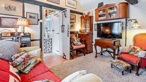 A cozy living room with a fireplace, a television, and a dining area with a wooden cabinet. - 1 Bed in Lymington (oc-94751) (Lymington)
