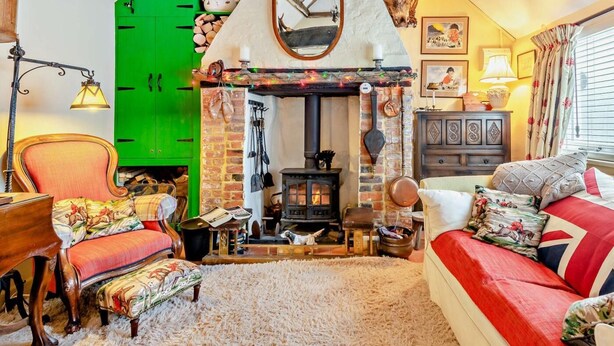 A cozy room with a fireplace, green wall, wooden furniture, and a red sofa. - 1 Bed in Lymington (oc-94751) (Lymington)
