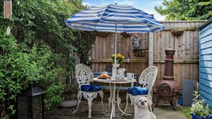 A patio with a table, chairs, a dog, and a blue and white striped umbrella. - 1 Bed in Lymington (oc-94751) (Lymington)