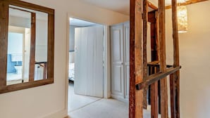 A hallway with a wooden staircase, a large mirror, and a door leading to a bedroom. - 3 Bed in Salisbury (oc-95325) (Amesbury)