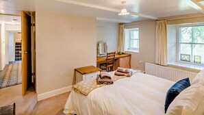 Une chambre à coucher avec un lit, un bureau, une chaise, une fenêtre avec des rideaux et un radiateur.