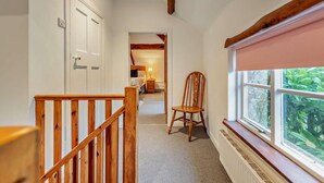 A hallway with a wooden staircase, a radiator, a window with a view of greenery, and a door leading to a bedroom. - 2 Bed in Exeter (oc-93129) (Crediton Hamlets)