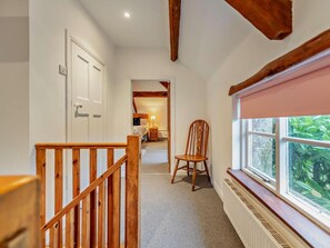 A hallway with a wooden staircase, a radiator, a window with a view of greenery, and a door leading to a bedroom. - 2 Bed in Exeter (oc-93129) (Crediton Hamlets)