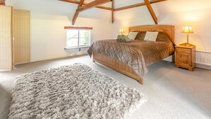 A bedroom with a wooden bed, a nightstand, a window, and a fluffy rug. - 2 Bed in Exeter (oc-93129) (Crediton Hamlets)