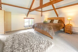 A bedroom with a wooden bed, a nightstand, a window, and a fluffy rug. - 2 Bed in Exeter (oc-93129) (Crediton Hamlets)