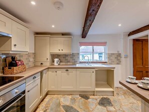 A kitchen with stone flooring, a window with a view, and a wooden ceiling beam. - 2 Bed in Exeter (oc-93129) (Crediton Hamlets)