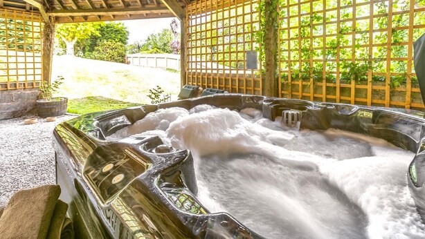 A hot tub with a wooden structure and a view of a garden. - 2 Bed in Exeter (oc-93129) (Crediton Hamlets)