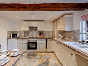 A kitchen with white cabinets, a stone backsplash, a built-in oven, a microwave, and a sink. - 2 Bed in Exeter (oc-93129) (Crediton Hamlets)