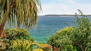 En trädgård vid kusten med utsikt över havet och ett landområde i fjärran.