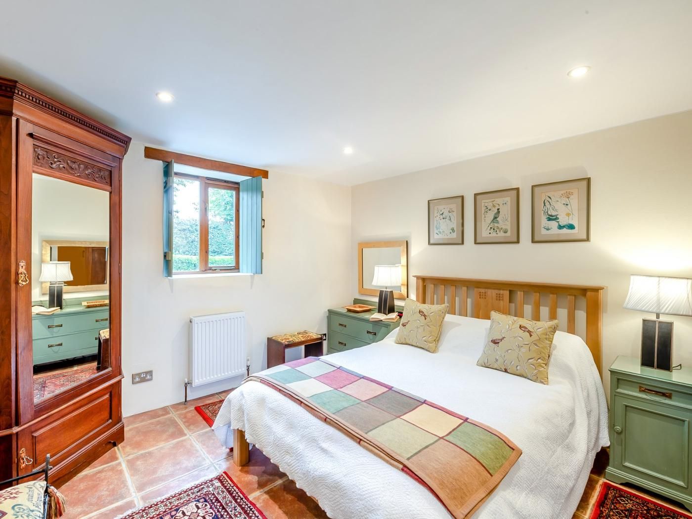 Une chambre à coucher avec un grand lit, une commode, une table de chevet, une fenêtre et des œuvres d’art murales.