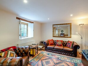 A cozy living room with a leather sofa, a chess table, and a patterned rug. - 5 Bed in Torrington (oc-knawo) (Frithelstock)