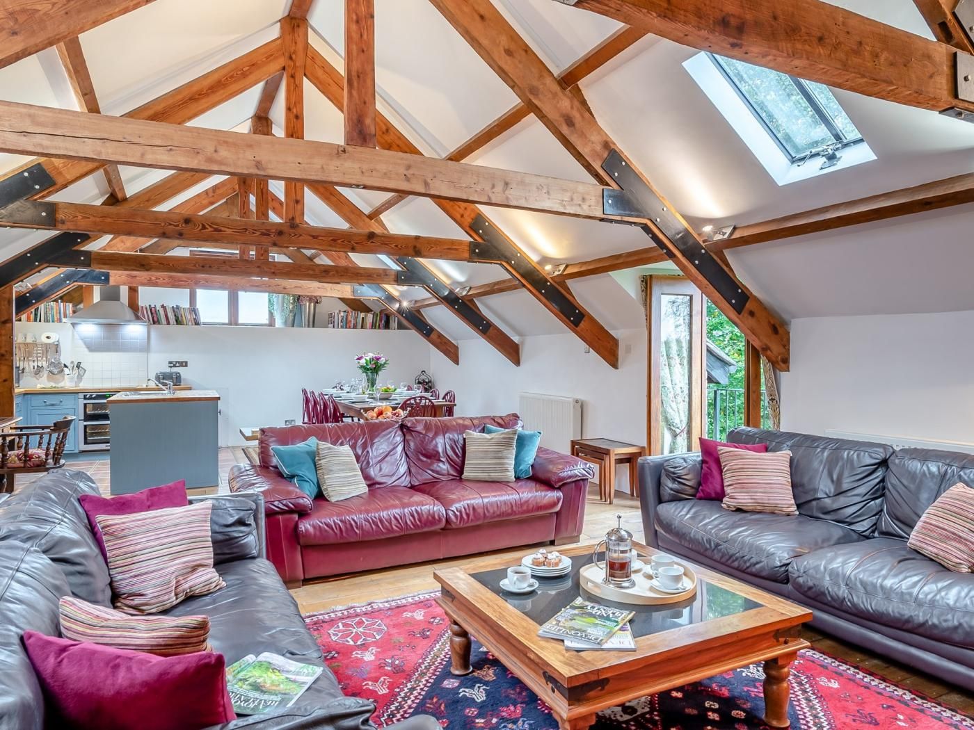A spacious loft with exposed wooden beams, a dining area, and a cozy seating arrangement.