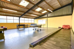 A spacious indoor area with a ping pong table, a foosball table, and a whiteboard on a yellow wall. - 5 Bed in Torrington (oc-knawo) (Frithelstock)