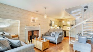 A living room with a fireplace, wooden flooring, a sofa, a coffee table, and a staircase. - 2 Bed in Carnforth (oc-95452) (Kirkby Lonsdale)