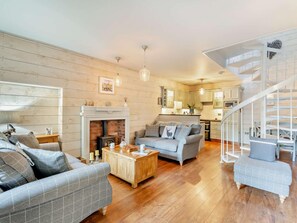 A living room with a fireplace, wooden flooring, a sofa, a coffee table, and a staircase. - 2 Bed in Carnforth (oc-95452) (Kirkby Lonsdale)