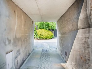 A concrete corridor with a stone pathway leading to a green bush. - 2 Bed in Carnforth (oc-95452) (Kirkby Lonsdale)
