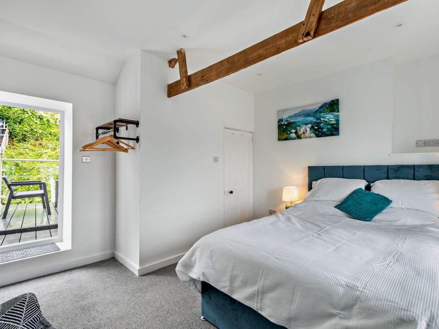 Een slaapkamer met een bed, nachtkastje, raam en deur.