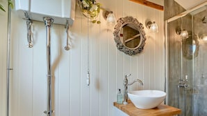 A bathroom with a white sink, a mirror, a shower, and a toilet paper holder. - 1 Bed in Broxburn (oc-95472) (Broxburn)