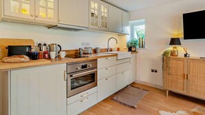Une cuisine moderne avec des meubles blancs, un four encastré et une fenêtre qui laisse entrer la lumière naturelle.