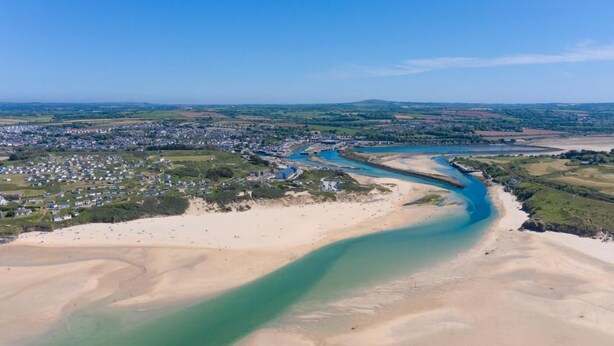 Vue aérienne d’une zone côtière avec une rivière, des plages de sable et une zone résidentielle.
