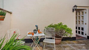 A patio with a table and chairs, a potted plant, and a door with a number. - 1 Bed in Penmaenmawr (oc-95495) (Penmaenmawr)
