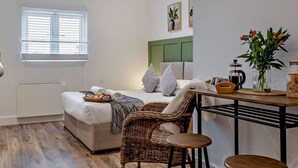 Een moderne slaapkamer met een bed, een eettafel en een rieten stoel.