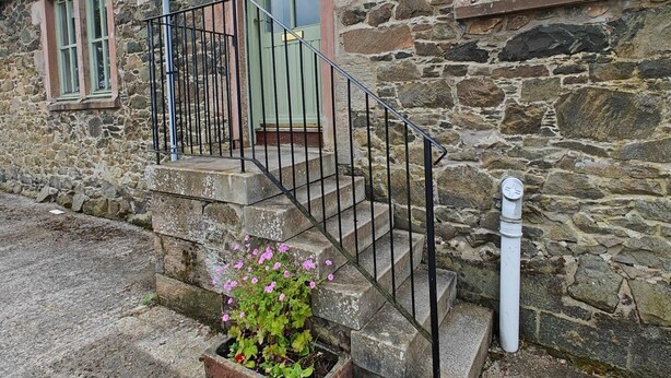 Un edificio de piedra con una escalera, una puerta y un ventanal.