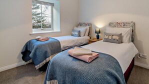 Un dormitorio con dos camas, una ventana y una mesita de noche con lámpara.