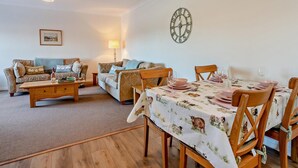 Una sala de estar acogedora con un conjunto de sofá, una mesa de centro de madera y una mesa de comedor para cuatro.